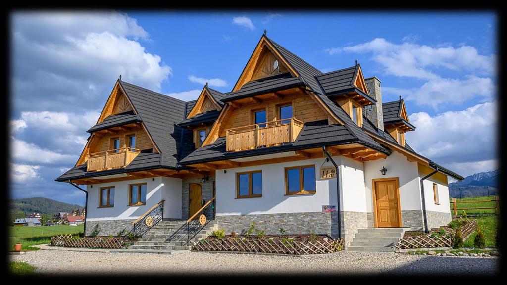 ein großes Haus mit Holzdach in der Unterkunft Apartamenty ROZETA Poronin in Poronin
