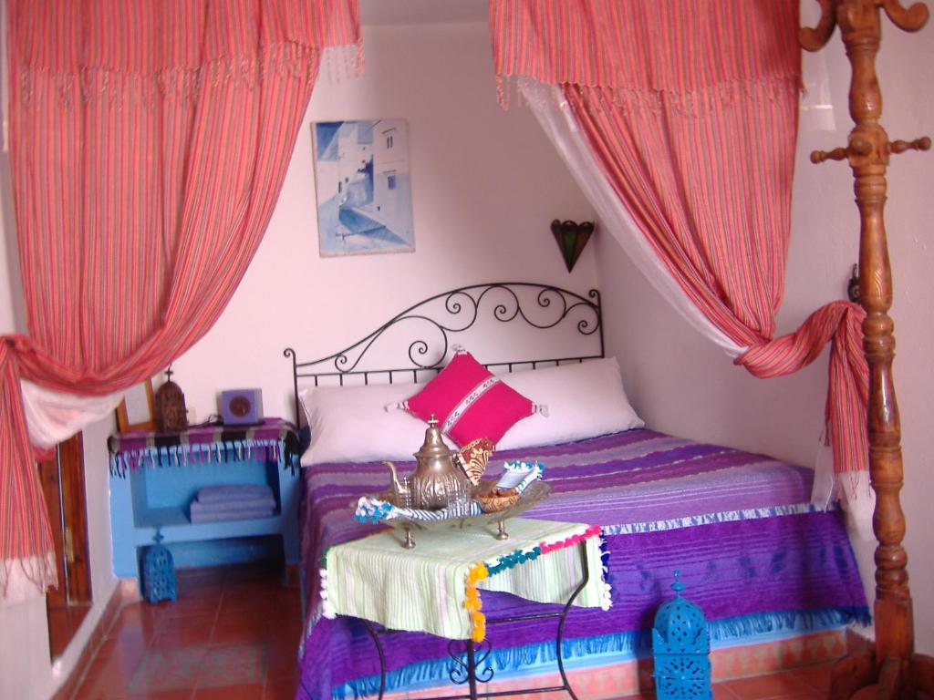 a bedroom with a bed with pink curtains and a bed with a bowl on top at Casa La Palma in Chefchaouene