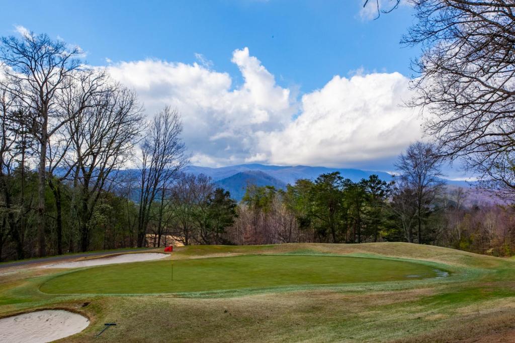 a green golf course with a view of the mountains at Higher Ground Condo with Mountain and Golf View in Pigeon Forge