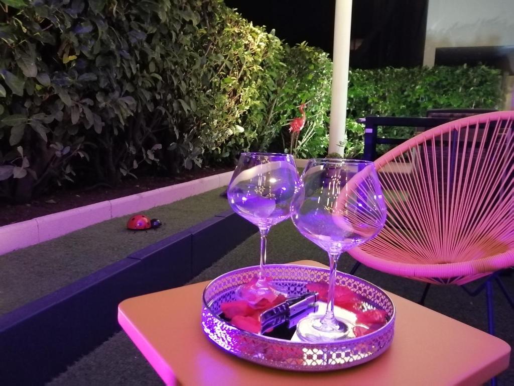 2 verres à vin assis sur un plateau sur une table dans l'établissement Romantisme et glamour 2 avec spa , clim et jardin, à Dijon