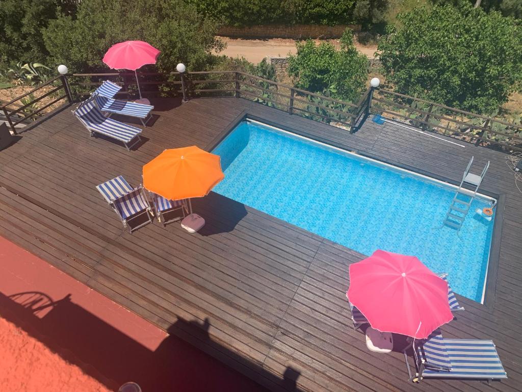 ein Pool mit zwei Sonnenschirmen und zwei Liegestühlen sowie ein Pool in der Unterkunft Le Dimore Del Sarto rooms in Polignano a Mare