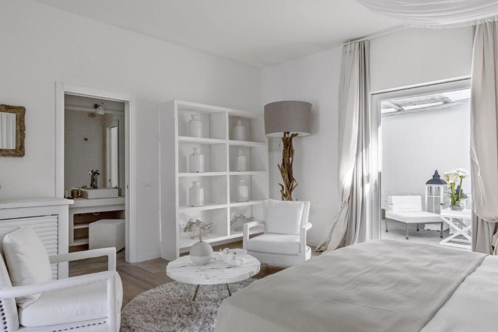 a white room with a bed and chairs and a table at Relais Corte Degli Aragonesi in Ischia