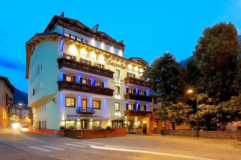 un grande edificio bianco con luci accese di notte di Hotel Sassella a Grosio