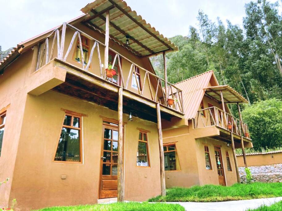 a large house with a balcony on top of it at Yuyay Wasi Bungalows in Urubamba