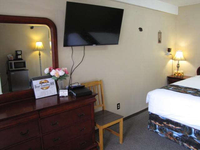 a bedroom with a bed and a dresser with a television on the wall at Bear Country Inn and Suites in Mountain View