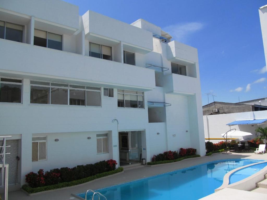 a white apartment building with a swimming pool at Hotel Kariary in Puerto Boyacá