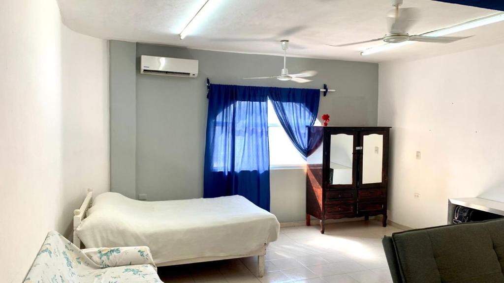1 dormitorio con 1 cama y una ventana con cortinas azules en Apartamento en Playa del Carmen, en Playa del Carmen