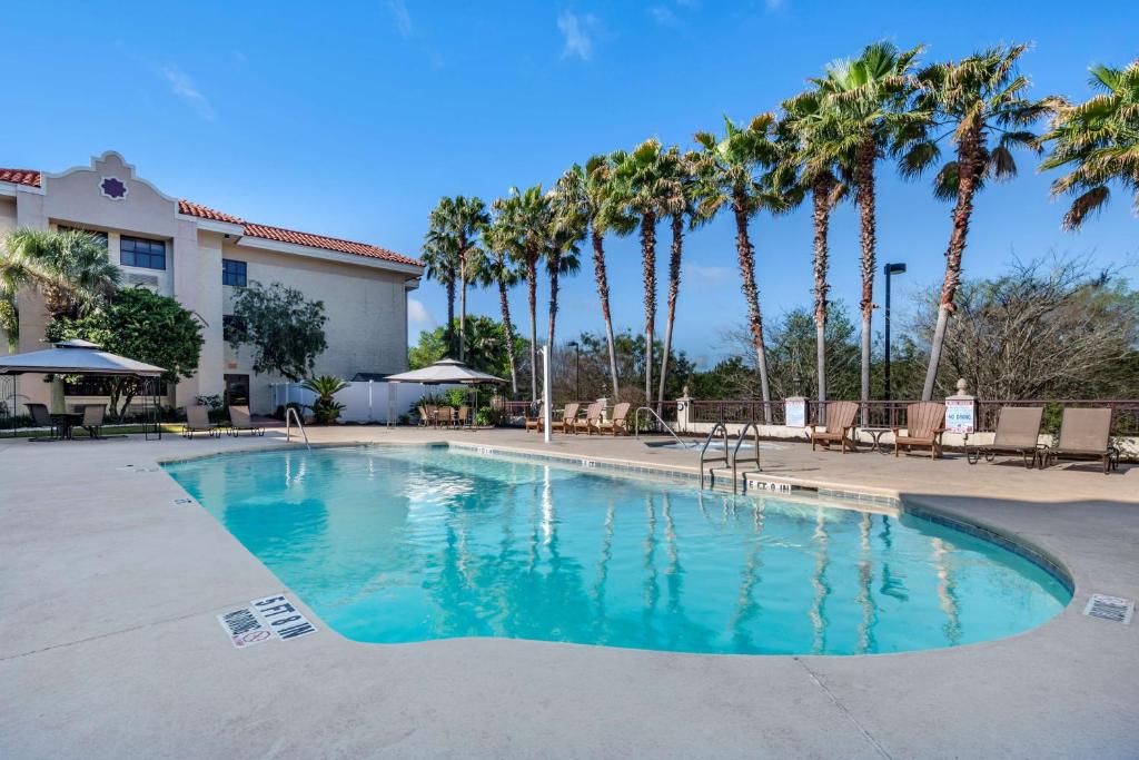 a swimming pool with palm trees in a resort at Best Western Gateway Grand in West Hills