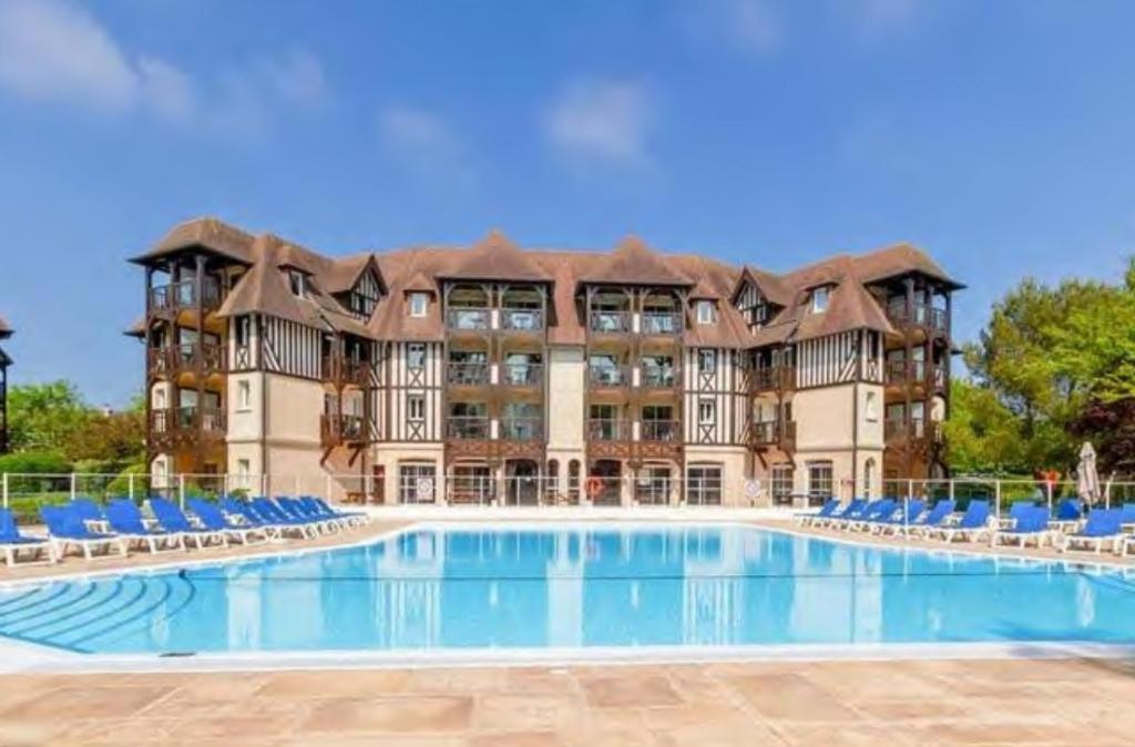 a large apartment building with a large swimming pool at LE COSY Résidence du Golf in Deauville
