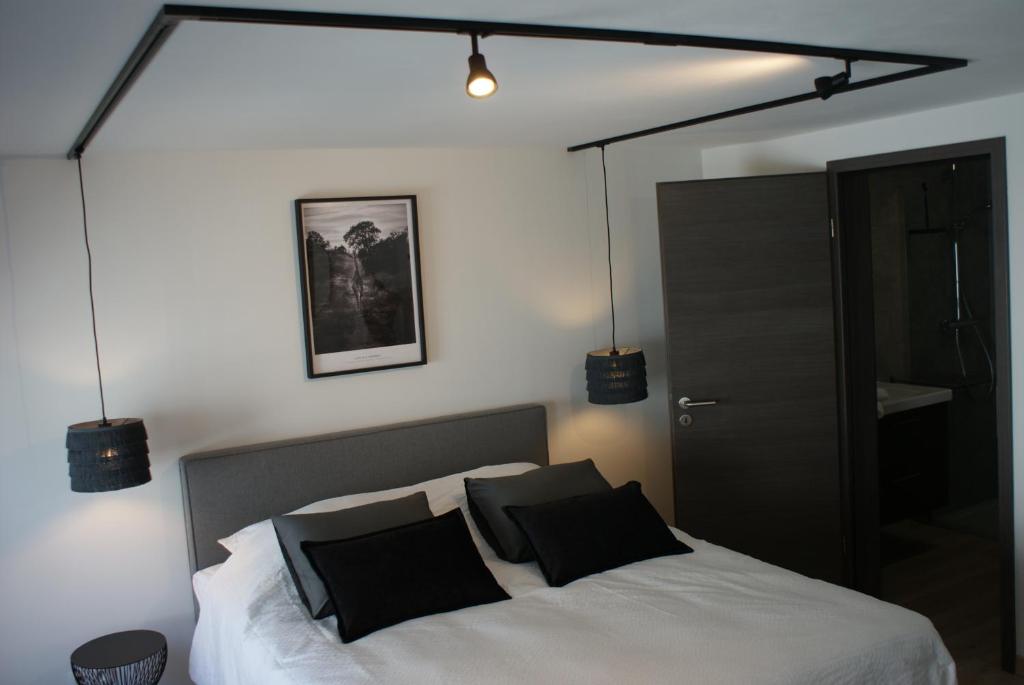 a bedroom with a white bed with black pillows at Les Clefs de Godefroy in Bouillon
