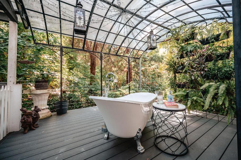 a bath tub on a deck with a greenhouse at Aldgate Valley Bed and Breakfast in Aldgate