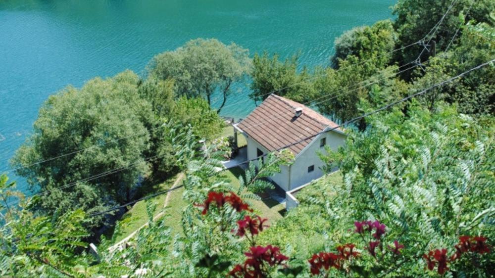 a house on top of a hill next to the water at Villa on the lake near Mostar in Jablanica