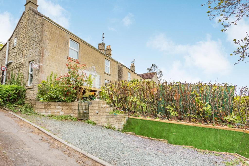 una casa de ladrillo con un jardín delante de ella en Hillside Cottage, en Bath