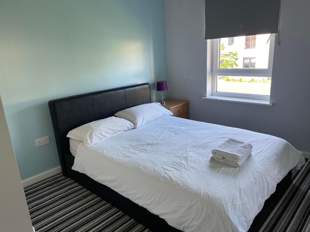 a bedroom with a bed with white sheets and a window at Newbuild - 3 bedrooms, 2 baths,5 mins from airport in Edinburgh
