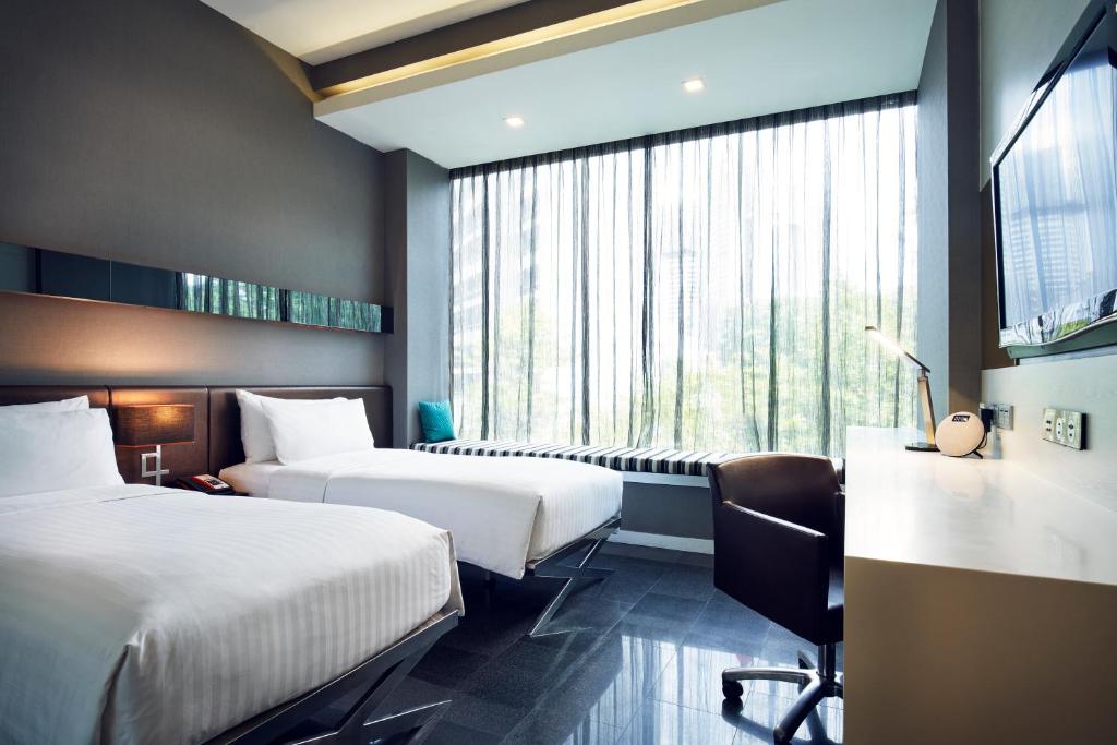 a hotel room with two beds and a window at Quincy Hotel Singapore by Far East Hospitality in Singapore