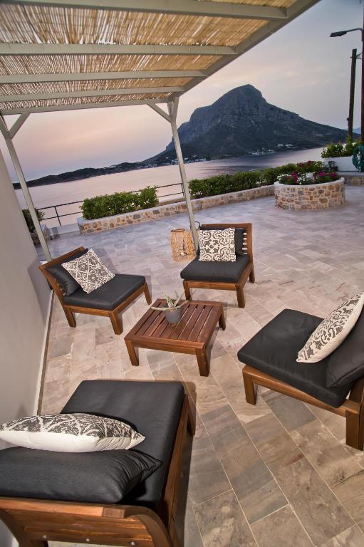a patio with chairs and tables and a view of the ocean at Horizon Hotel Kalymnos in Myrties