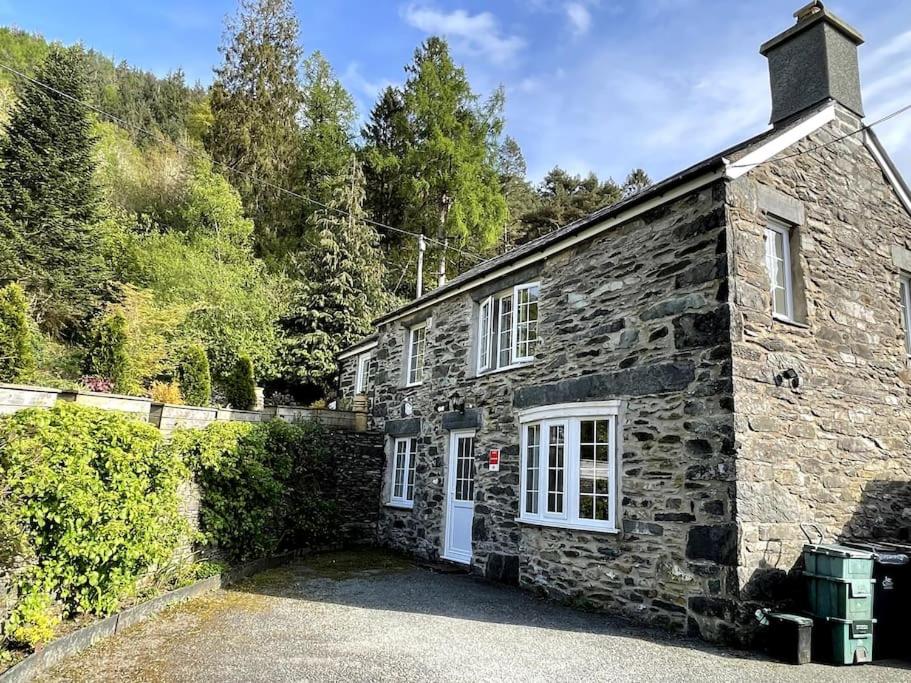 an old stone house with a white door at Cosy 2 Bedroom Cottage in Betws y Coed, Snowdonia in Betws-y-coed