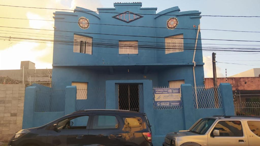 dos autos estacionados frente a un edificio azul en Pousada Cisne Branco en Natal