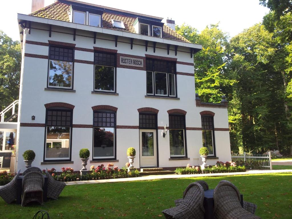 Bed & Breakfast Rijsterbosch في رايس: منزل أبيض بنوافذ سوداء وساحة