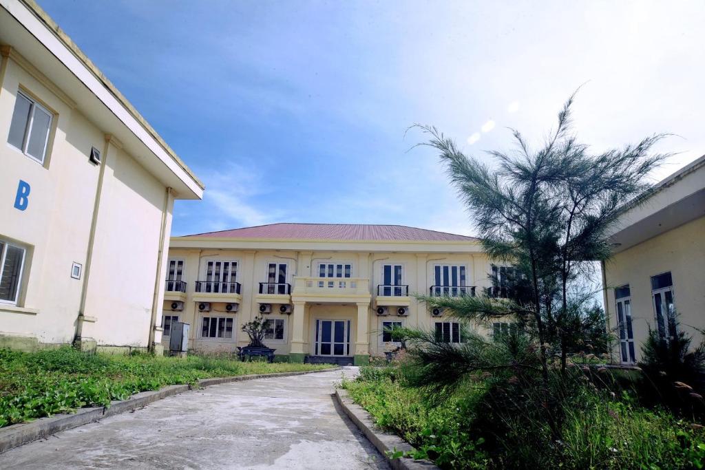 a building with a palm tree in front of it at Nhà khách Thanh niên Quảng Nam in Phú Quí (2)