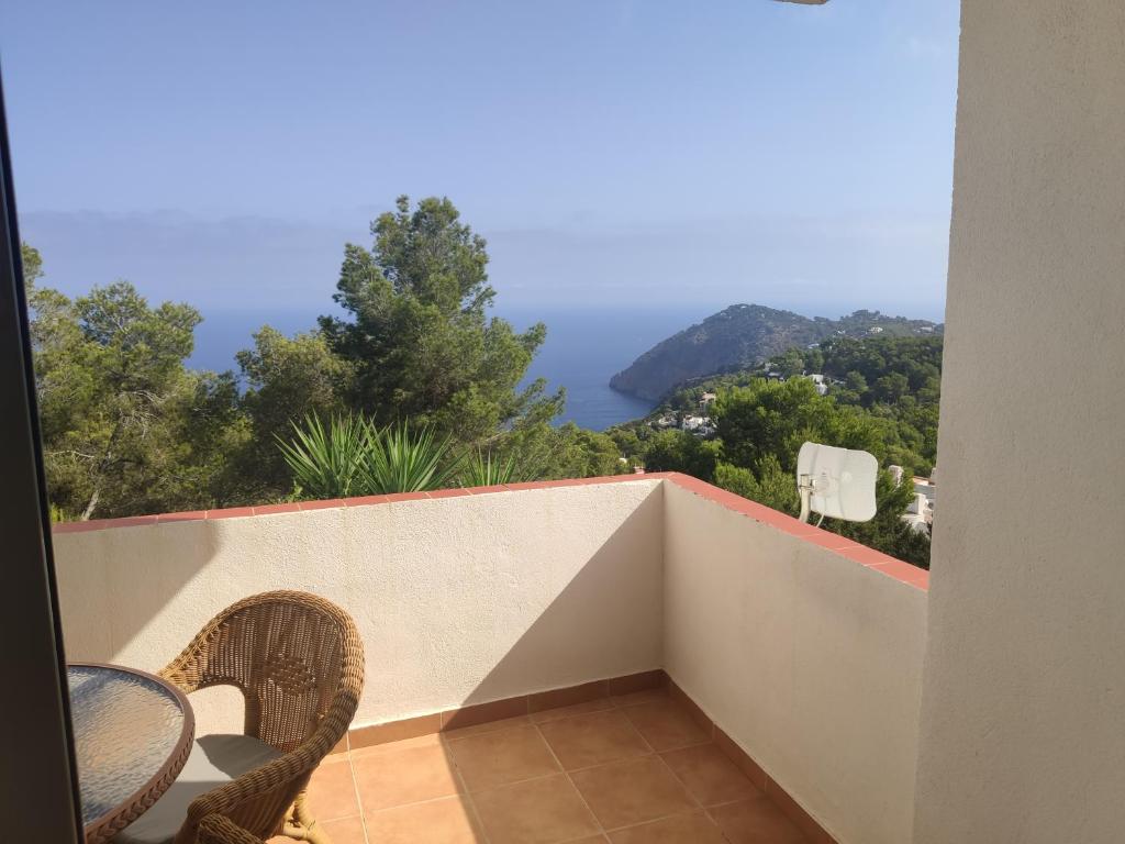 een balkon met een tafel en stoelen en uitzicht op de oceaan bij Semi-detached house, with an impressive view of the sea and the valley in Sant Joan de Labritja