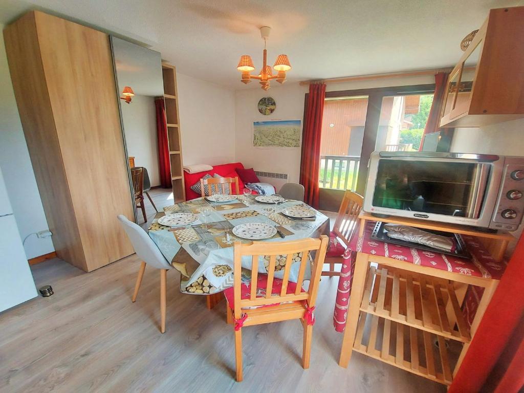 a dining room with a table with chairs and a television at Cosy appartement au centre de Morillon, proche télécabine, balcon et parking - FR-1-624-104 in Morillon
