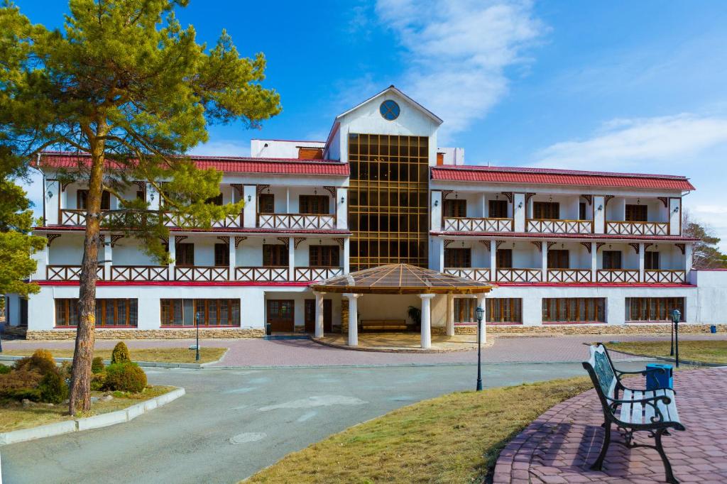 un edificio con un banco delante de él en Park Hotel Kokshetau, en Shchūchīnsk