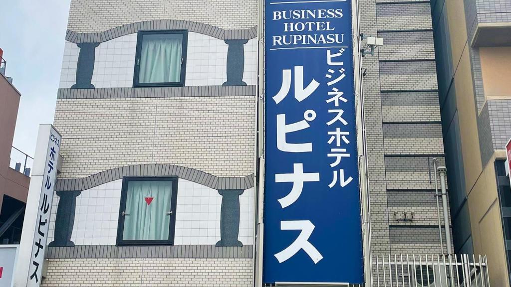 un bâtiment avec un panneau bleu sur son côté dans l'établissement Business Hotel Rupinasu, à Takamatsu