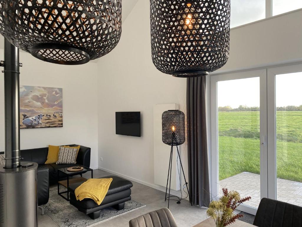 a living room with two large lights hanging from the ceiling at Kuh Blick Ferienhaus Sehestedt in Sehestedt