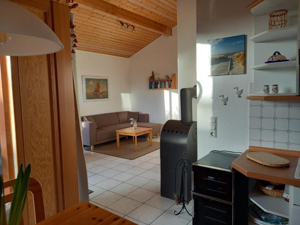 a kitchen with a refrigerator and a living room at Anne See Ferienhaus Sehestedt in Sehestedt