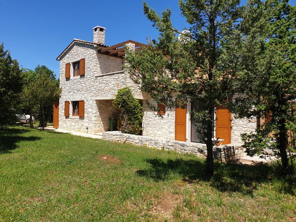 une maison en pierre avec un arbre en face de celle-ci dans l'établissement Villa Valeria, à Divšići