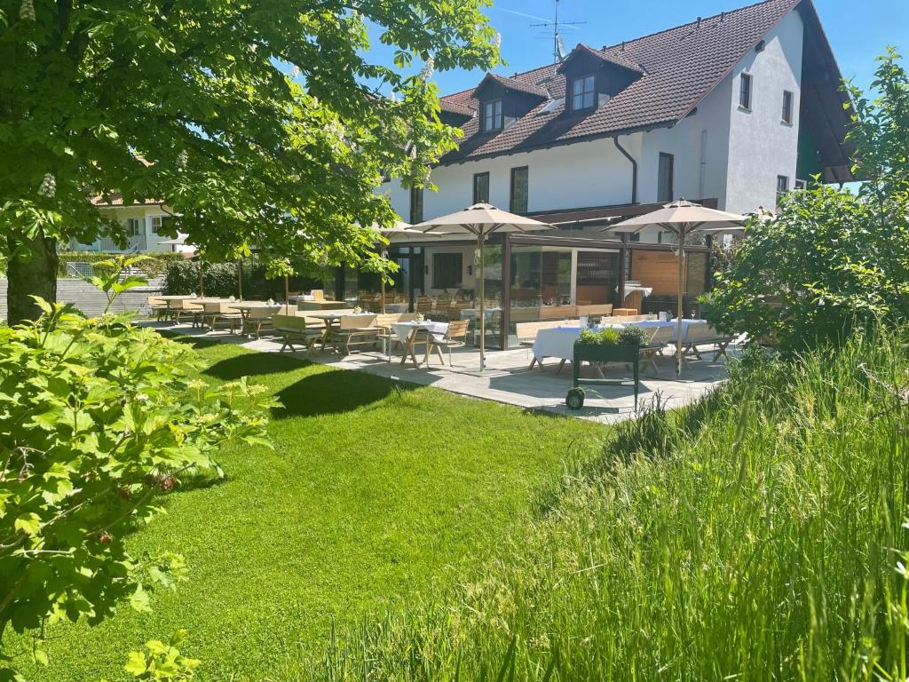 a building with tables and umbrellas in a yard at Hotel Restaurant Erber in Ismaning