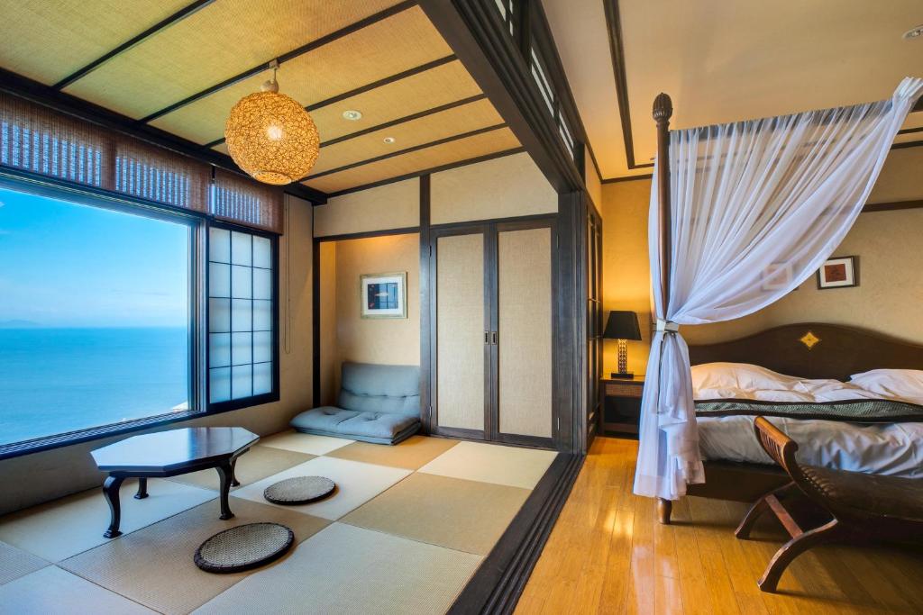 a bedroom with a bed and a table and a window at Ijika Daiichi Hotel Kagura in Toba