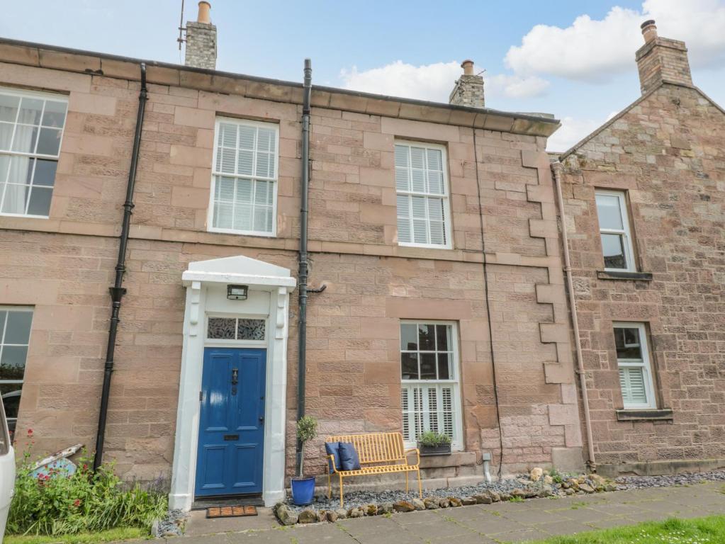 a brick building with a blue door and a bench at 8 Pedwell Way in Berwick-Upon-Tweed