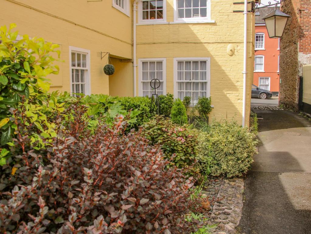 a yellow house with a hedge in front of it at 138C Old Star & Garter Mews in Ludlow