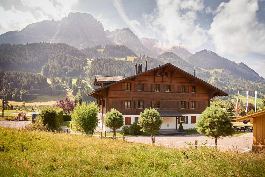 un gran edificio de madera con montañas en el fondo en Reka-Ferienanlage Rougemont, en Rougemont