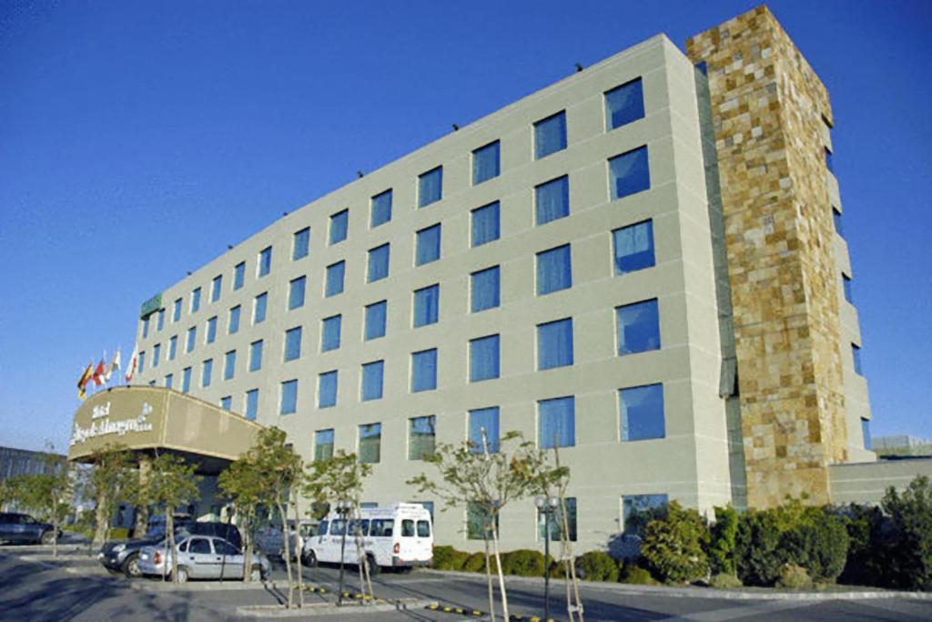 un gran edificio con un autobús estacionado frente a él en Hotel Diego de Almagro Aeropuerto en Santiago
