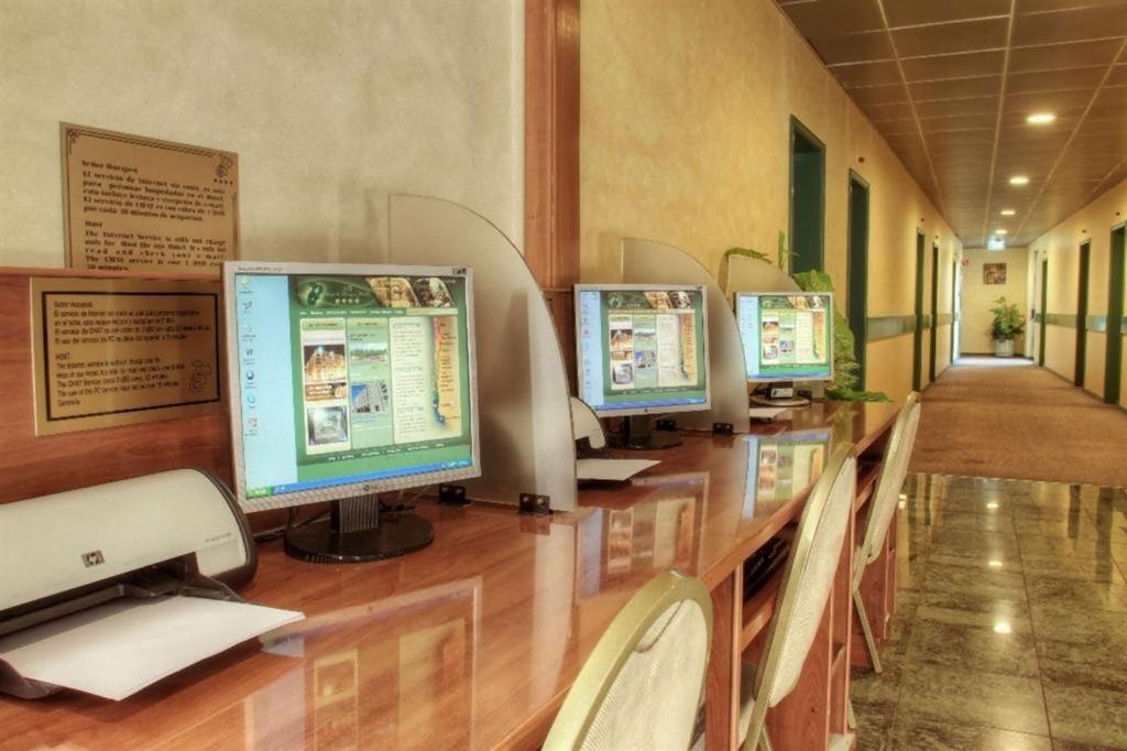 a row of computer monitors sitting on a desk at Hotel Diego de Almagro Aeropuerto in Santiago