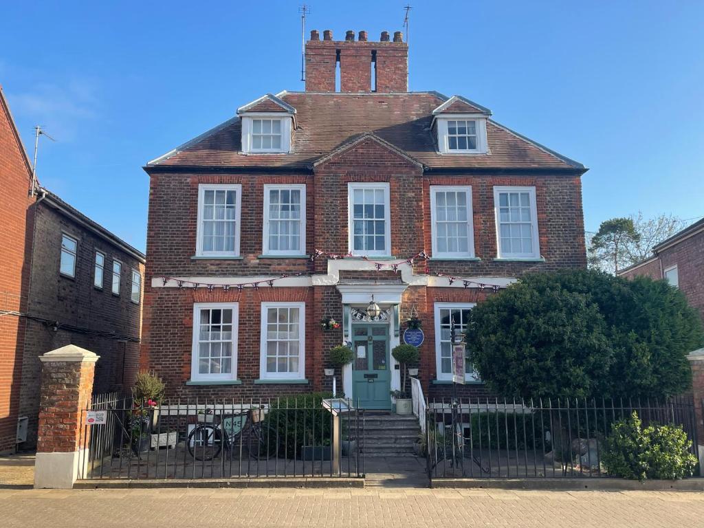 a red brick house with a blue door and a fence at The Mansion House Hotel in Holbeach