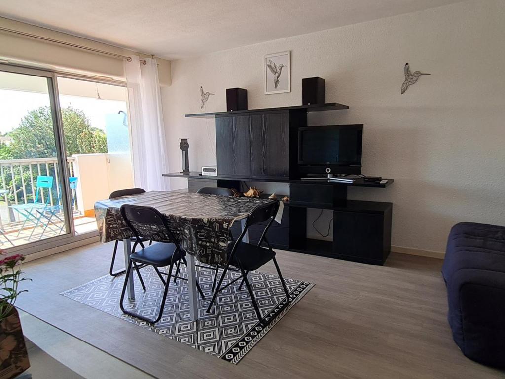 un salon avec une table, des chaises et une télévision dans l'établissement Appartement Ensoleillé avec Terrasse et Parking au Centre de Meschers, Proche Plages et Commerces - FR-1-550-38, à Meschers-sur-Gironde