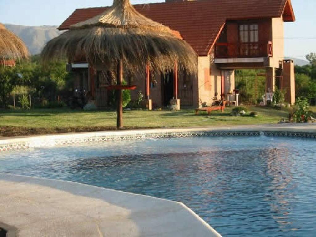 ein Haus mit einem Pool vor einem Haus in der Unterkunft Cabañas Oma Lissi in Merlo