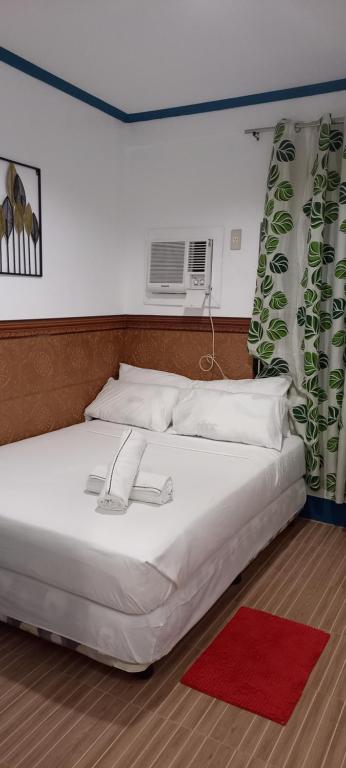 sypialnia z białym łóżkiem z czerwonym dywanem w obiekcie Camiguin VIAJEROS House Rental w mieście Compol