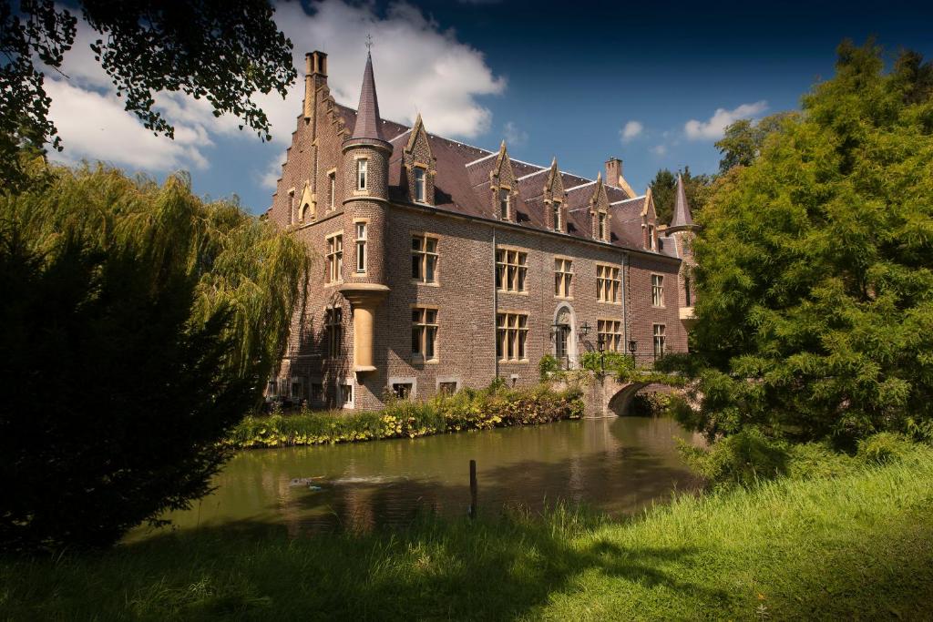 a large castle with a river in front of it at Van der Valk Hotel Kasteel Terworm in Heerlen