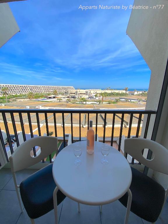 une table blanche et des chaises sur un balcon avec vue dans l'établissement Studios Héliopolis Village Naturiste, au Cap d'Agde