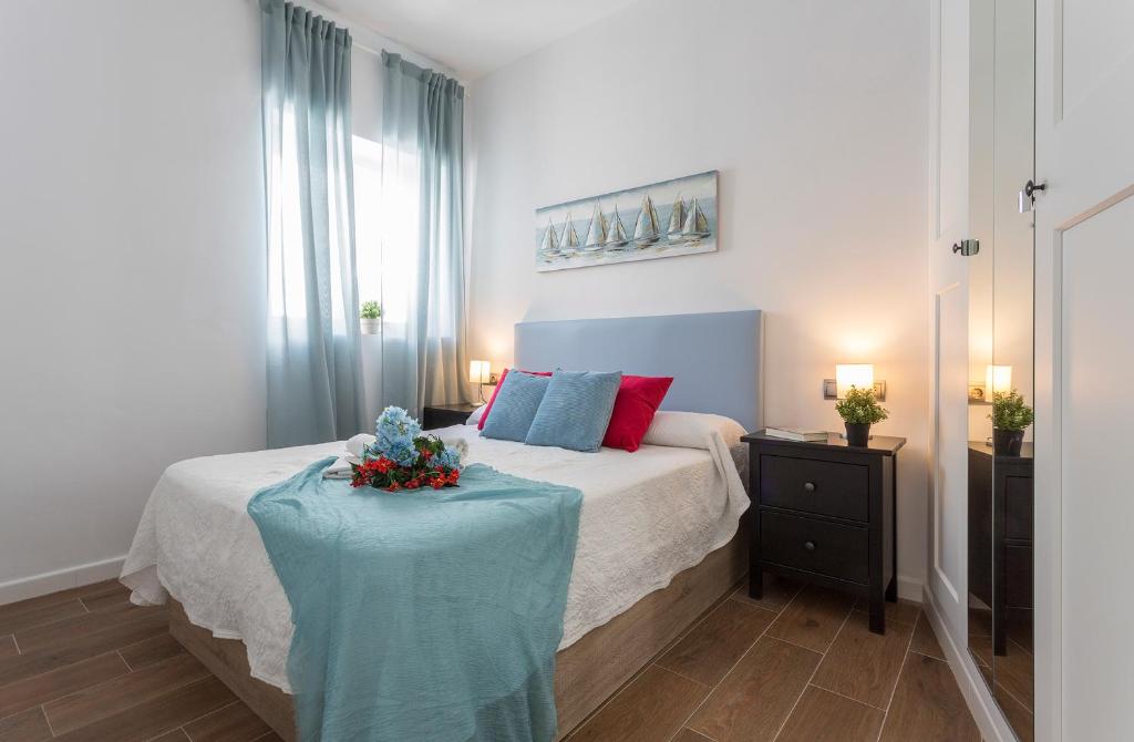 una camera da letto con un letto e un tavolo con dei fiori sopra di Doña Blanca Centro Diseño Minimalista a Jerez de la Frontera