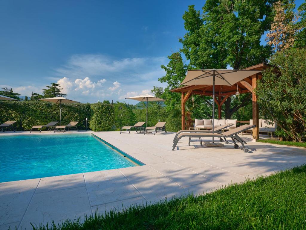 - une piscine avec un parasol, des chaises et une table avec un parasol dans l'établissement Cason degli Ulivi, à Rivoli Veronese