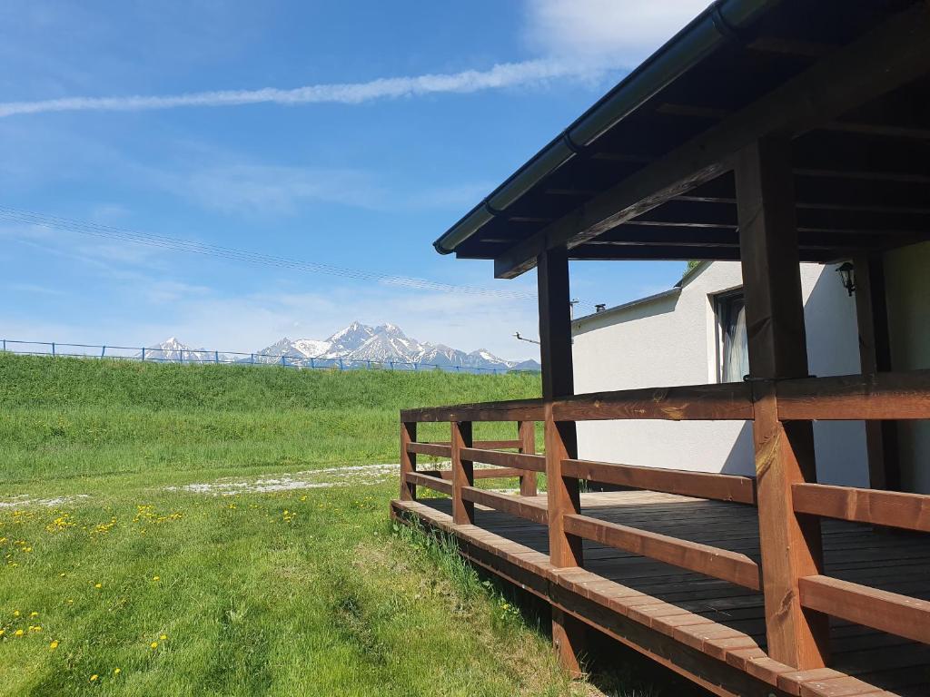 a building with a fence and mountains in the background at Chatka pod Tatrami in Mlynčeky