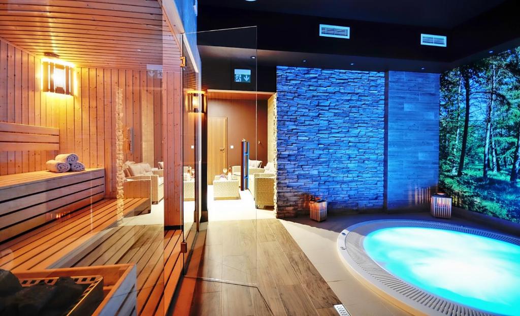 a bathroom with a large tub with a stone wall at Amberia in Grzybowo