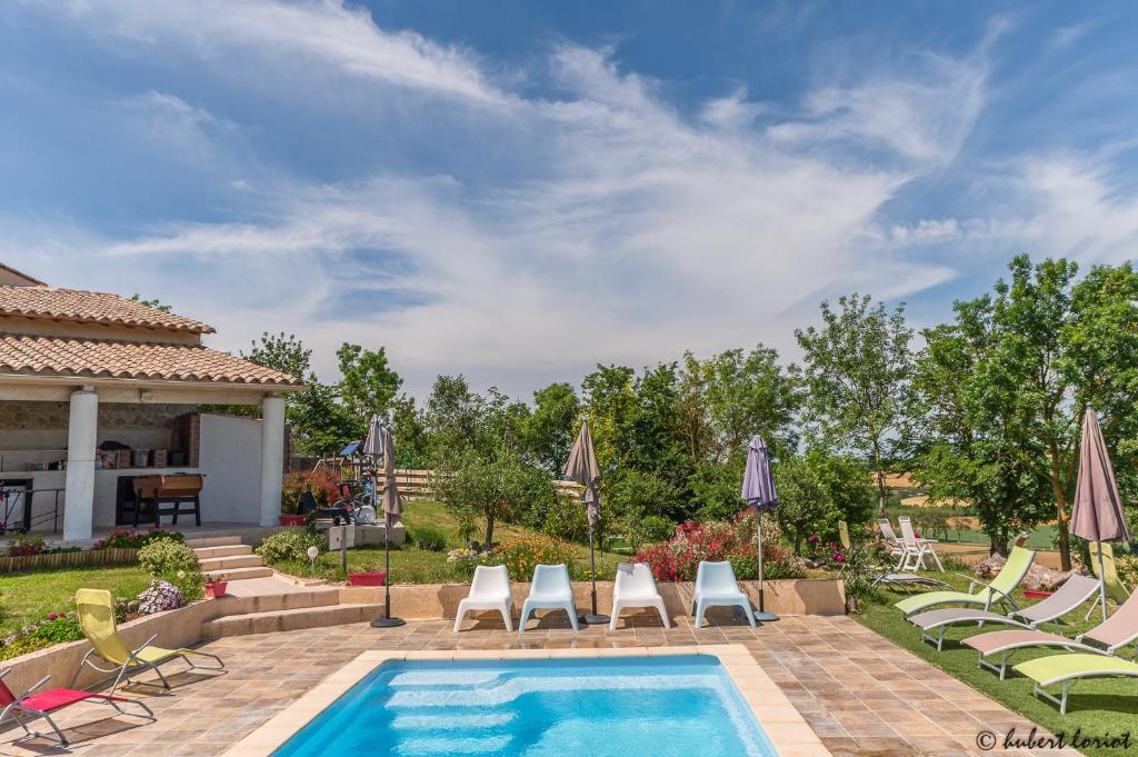 a backyard with a pool and chairs and a house at Gites Les Granges De Flolie in Beauteville