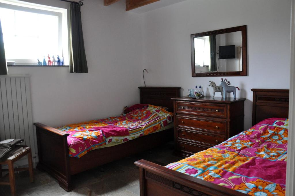 1 Schlafzimmer mit 2 Betten, einer Kommode und einem Spiegel in der Unterkunft B&B Kelpiebrink in Baarle-Nassau
